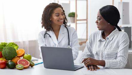Smiling black lady doctor chatting with female patient