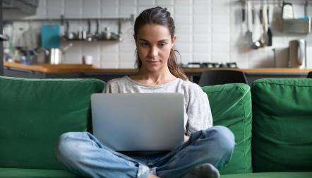Young woman sitting on a couch with a laptop