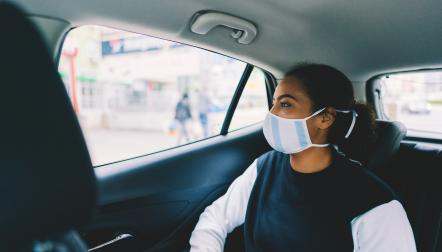 Woman sitting in back seat of car with a mask on
