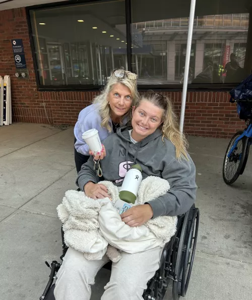 Jackie Medici in a wheelchair with mother behind her