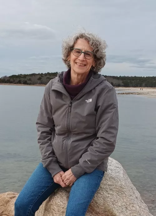 Robin M. sitting on a rock in front of a body of water
