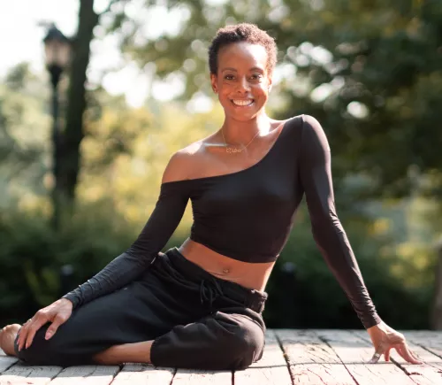 Victoria Gibbs sitting in athleisure outfit on a platform in the woods