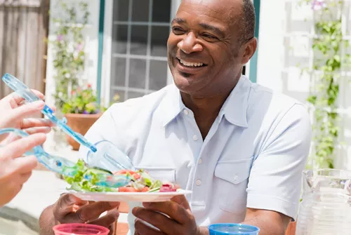 Man being served a salad in backyard.