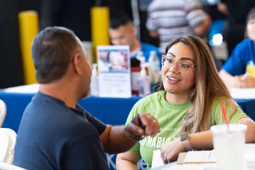 photo of Julie Cisneros talking to a man at a table.