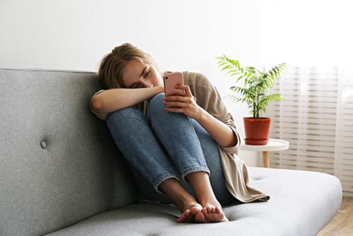 woman sitting on couch looking at eye phone.