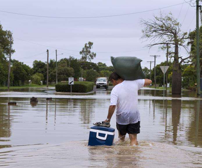 man carrying supplies in flood