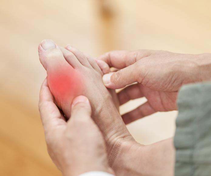 A person holding their foot due to toe gout pain