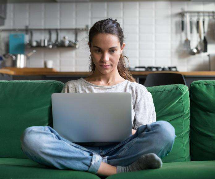 Young woman sitting on a couch with a laptop