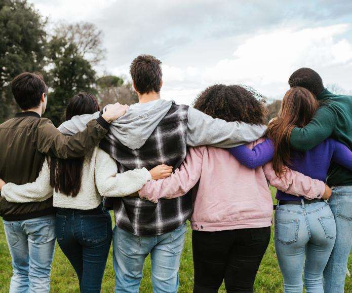 Diverse group of friends hugging shot from behind