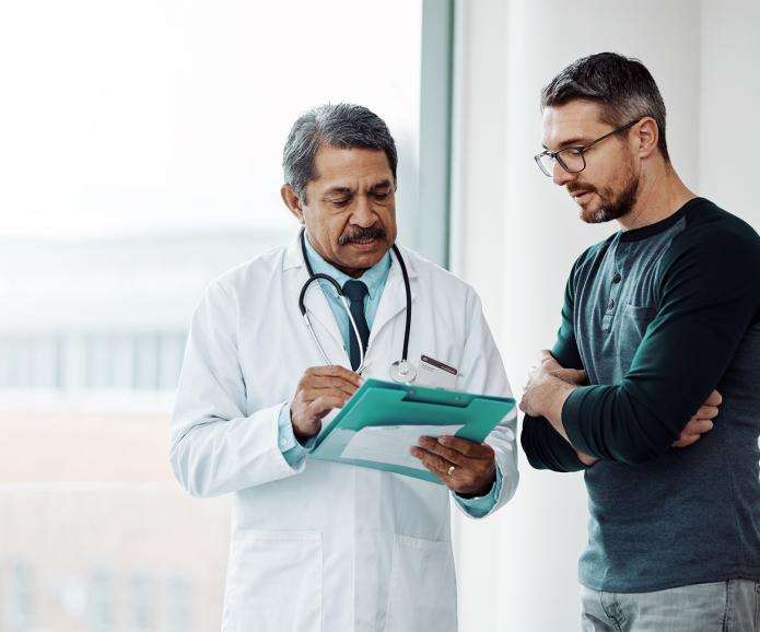 Older Hispanic doctor talking to a white male patient
