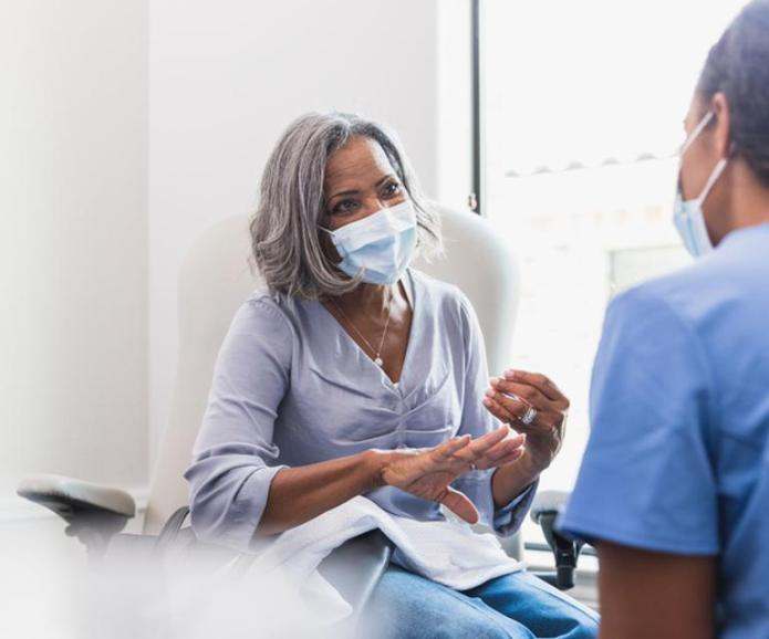 Woman with mask talking to doctor