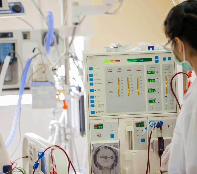 A dialysis technician looking at a dialysis machine