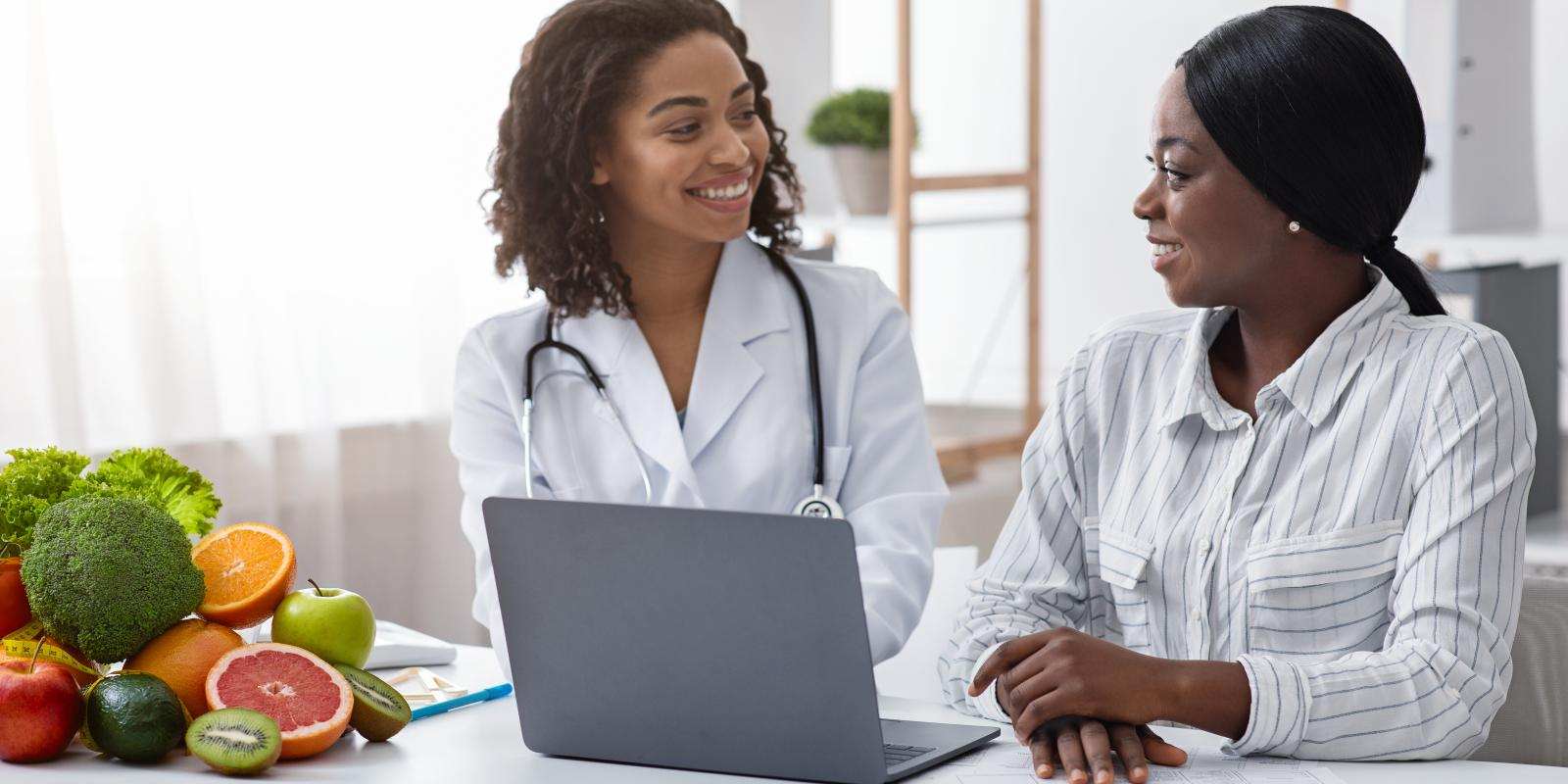 Smiling black lady doctor chatting with female patient