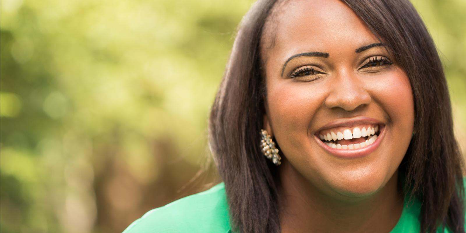black woman smiling green shirt outside